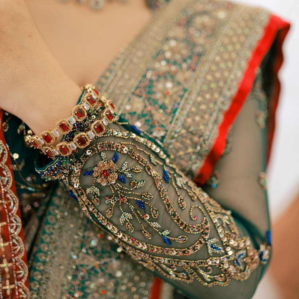 Hand-embroidered emerald threadwork under a jewelled cuff