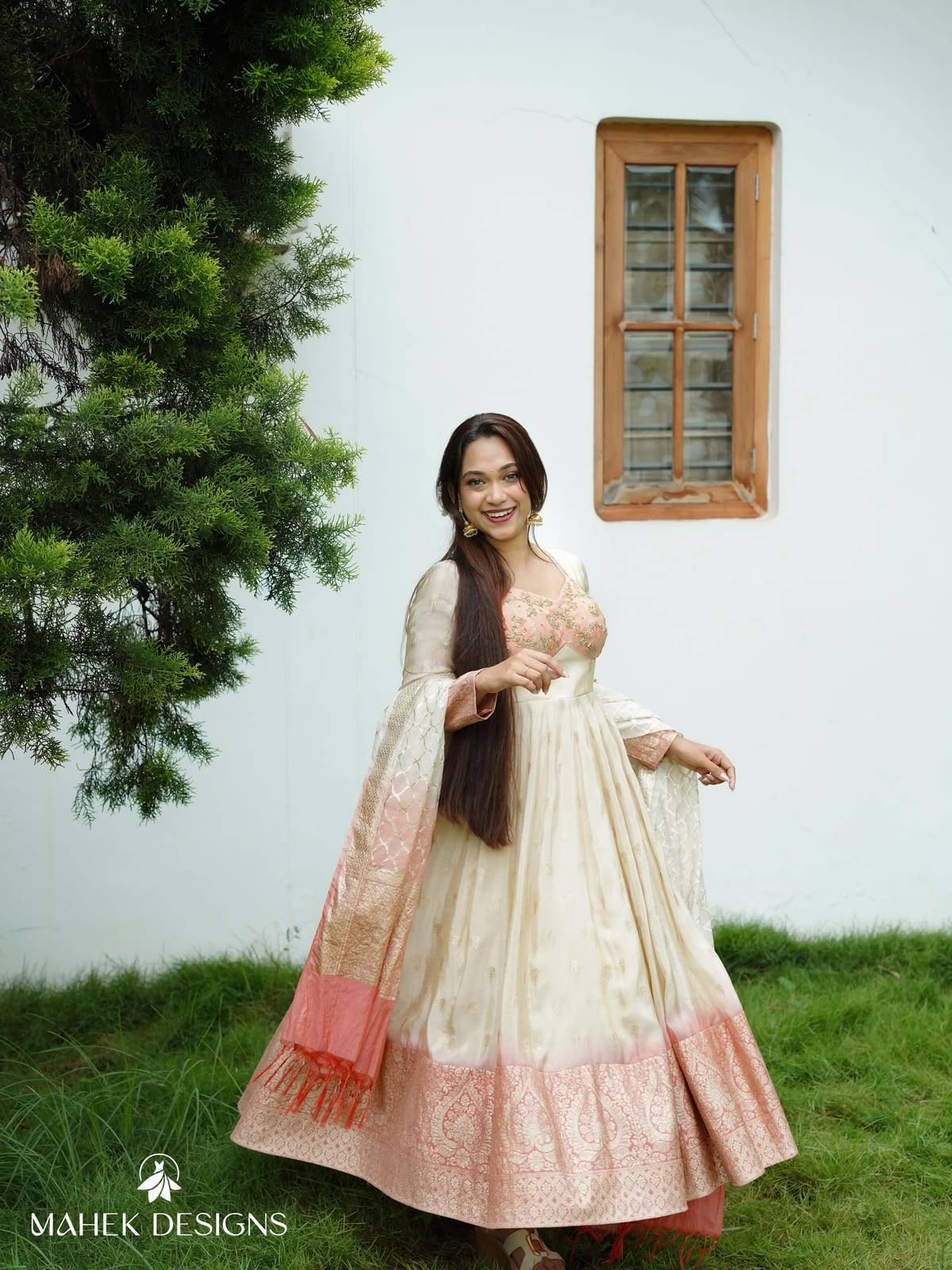 A graceful fusion of traditional elegance and contemporary charm, this ensemble features a soft ivory Anarkali crafted in a rich, flowing fa